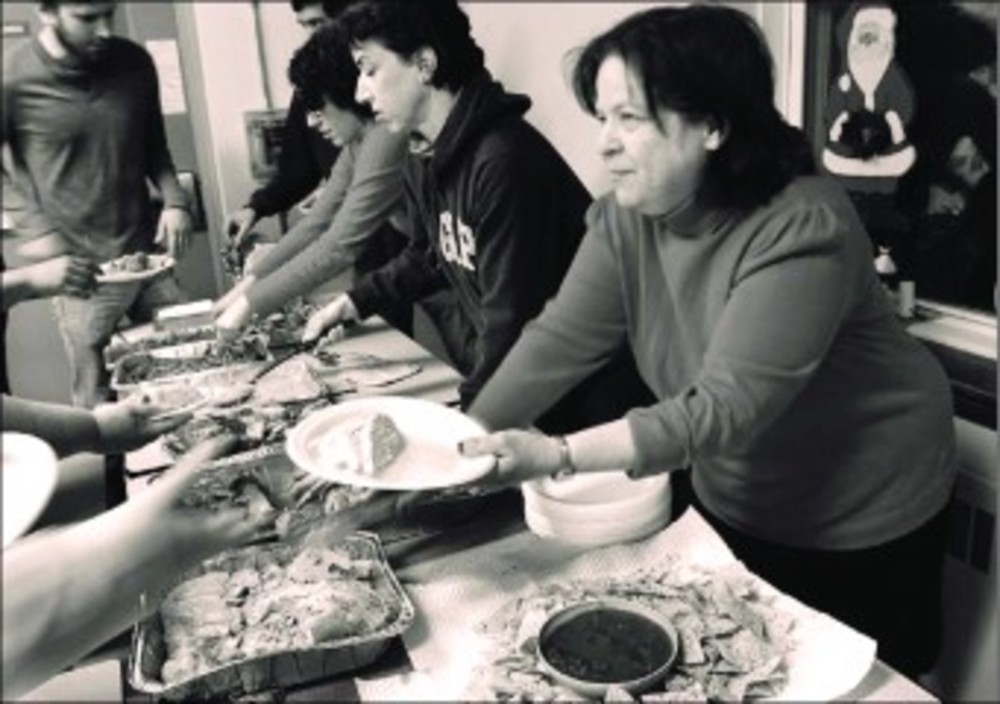 Marcia Slobin, front, right, a Torat Yisrael board member, and Laura Steele, a Torat Yisrael member and congregation librarian, serve Kosher Christmas dinner to the residents of  the Rhode Island Family Shelter. /The Jewish Voice